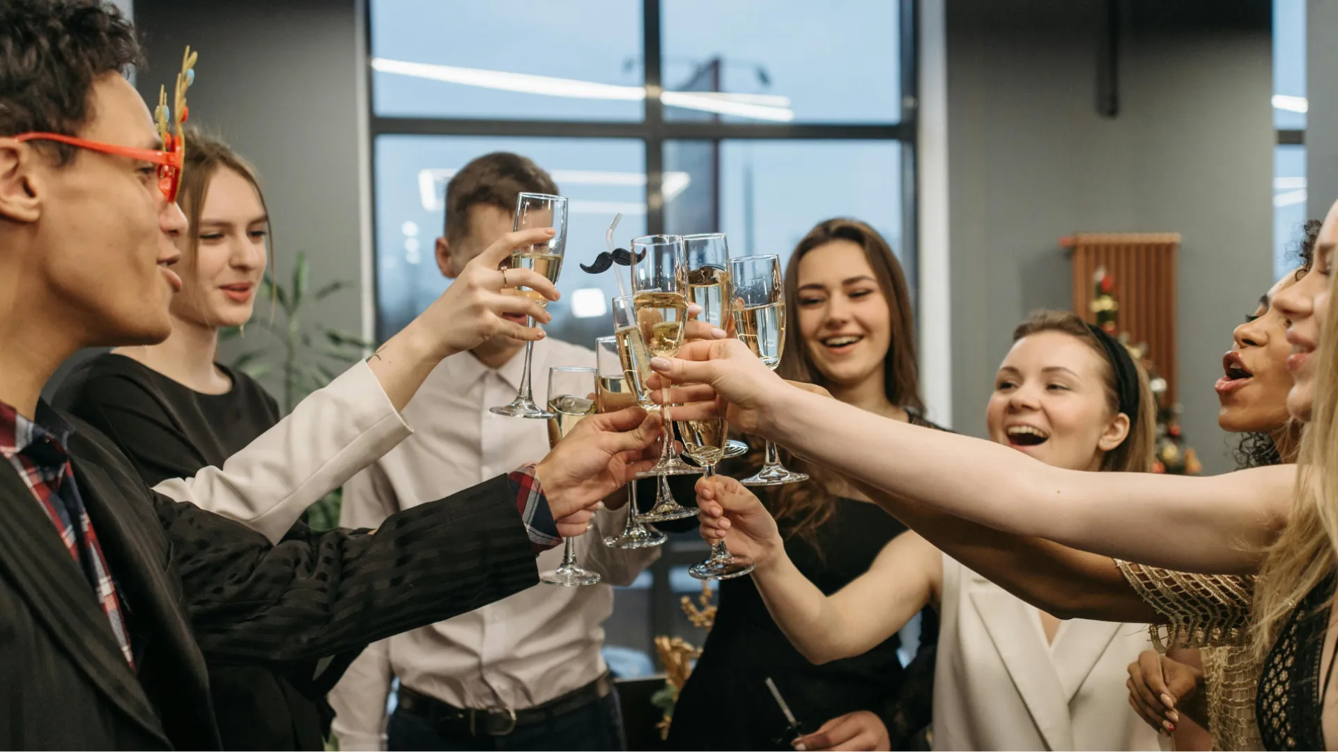 Friends raising champagne glasses in celebration at lively indoor party with festive atmosphere