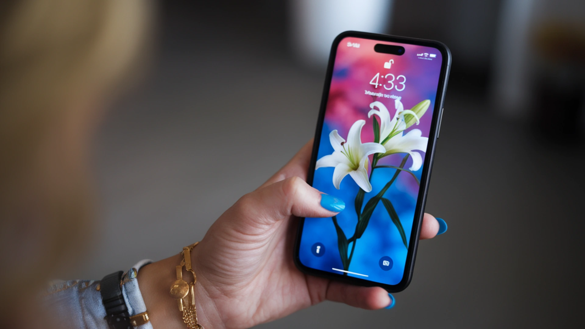 Hand holding iPhone with lock screen showing time and flower wallpaper, modern smartphone display in focus