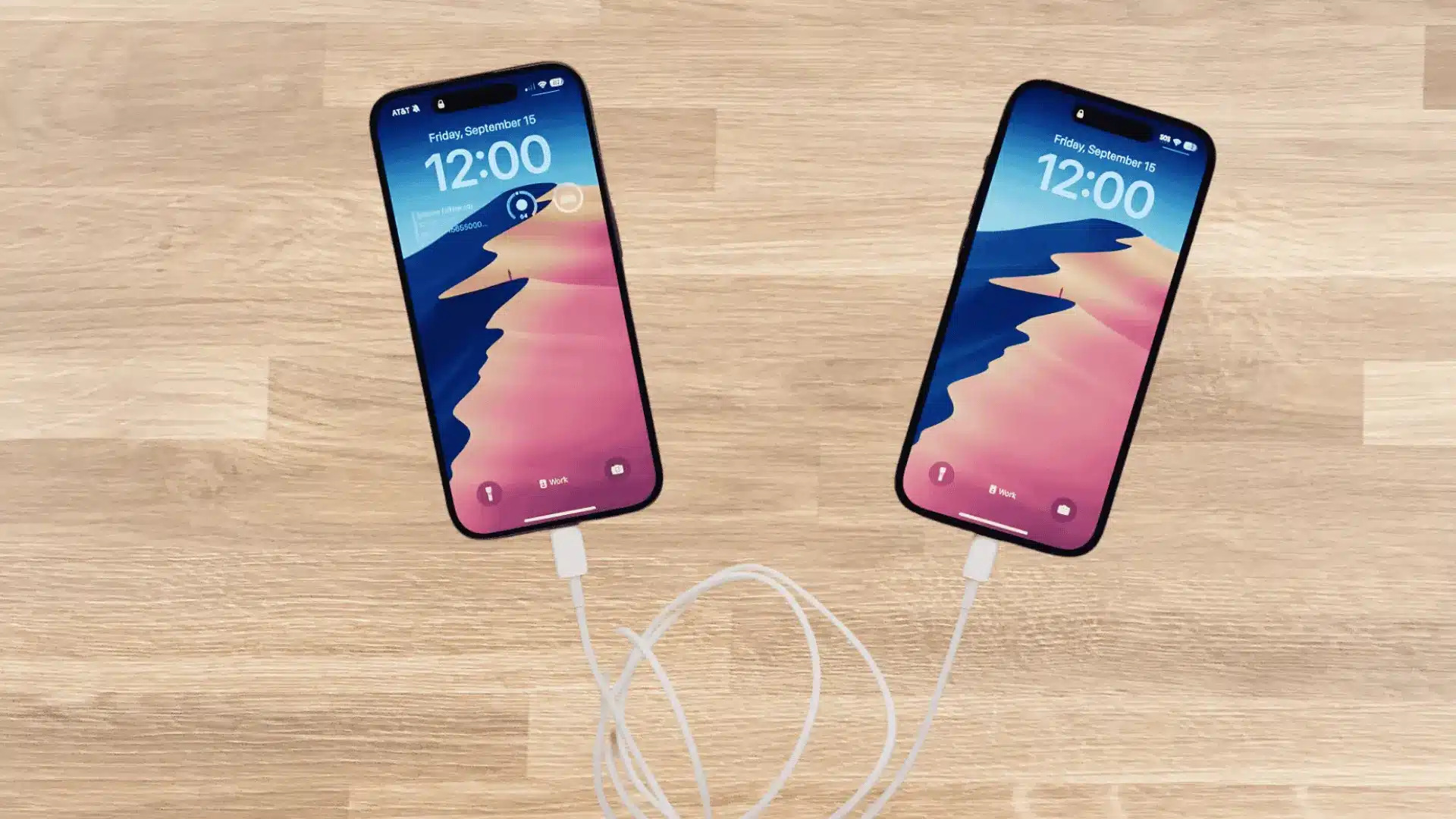 Two iPhones connected with charging cable on wooden floor demonstrating direct device charging setup