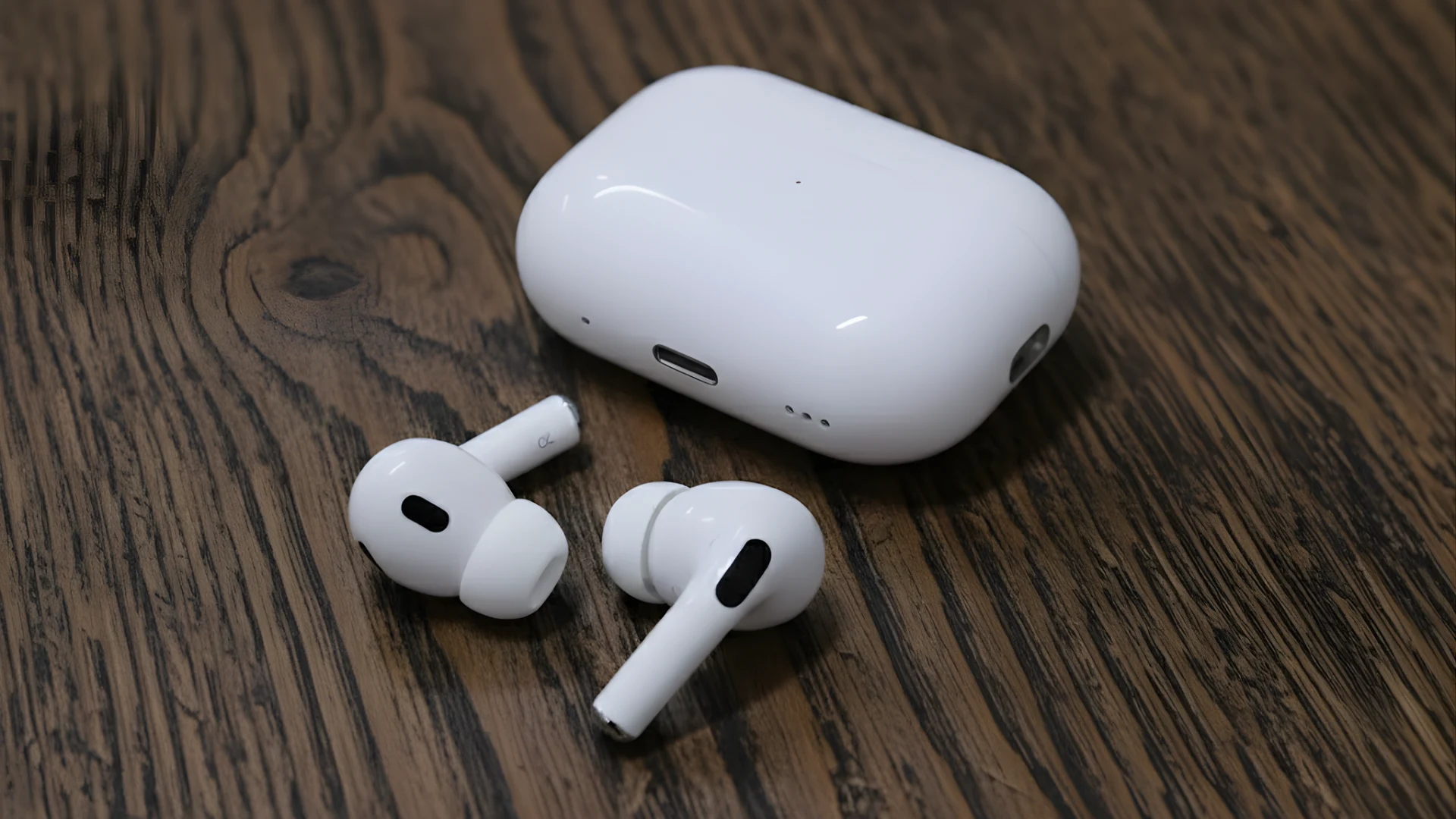 Apple AirPods Pro earbuds and white charging case placed on a textured wooden table surface