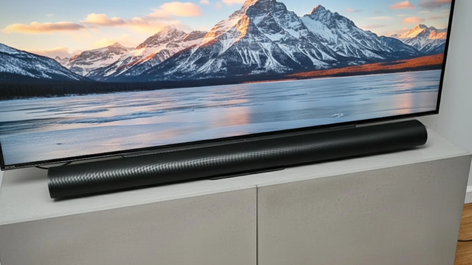 Sonos Arc Ultra soundbar placed below a large TV displaying mountain landscape on a modern white media console