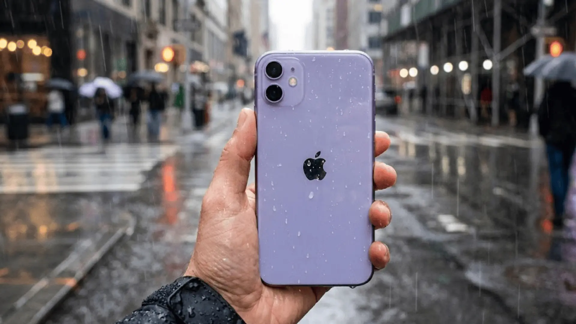 A first-person view of a hand holding a purple iPhone 11 covered in raindrops on a wet, blurry city street