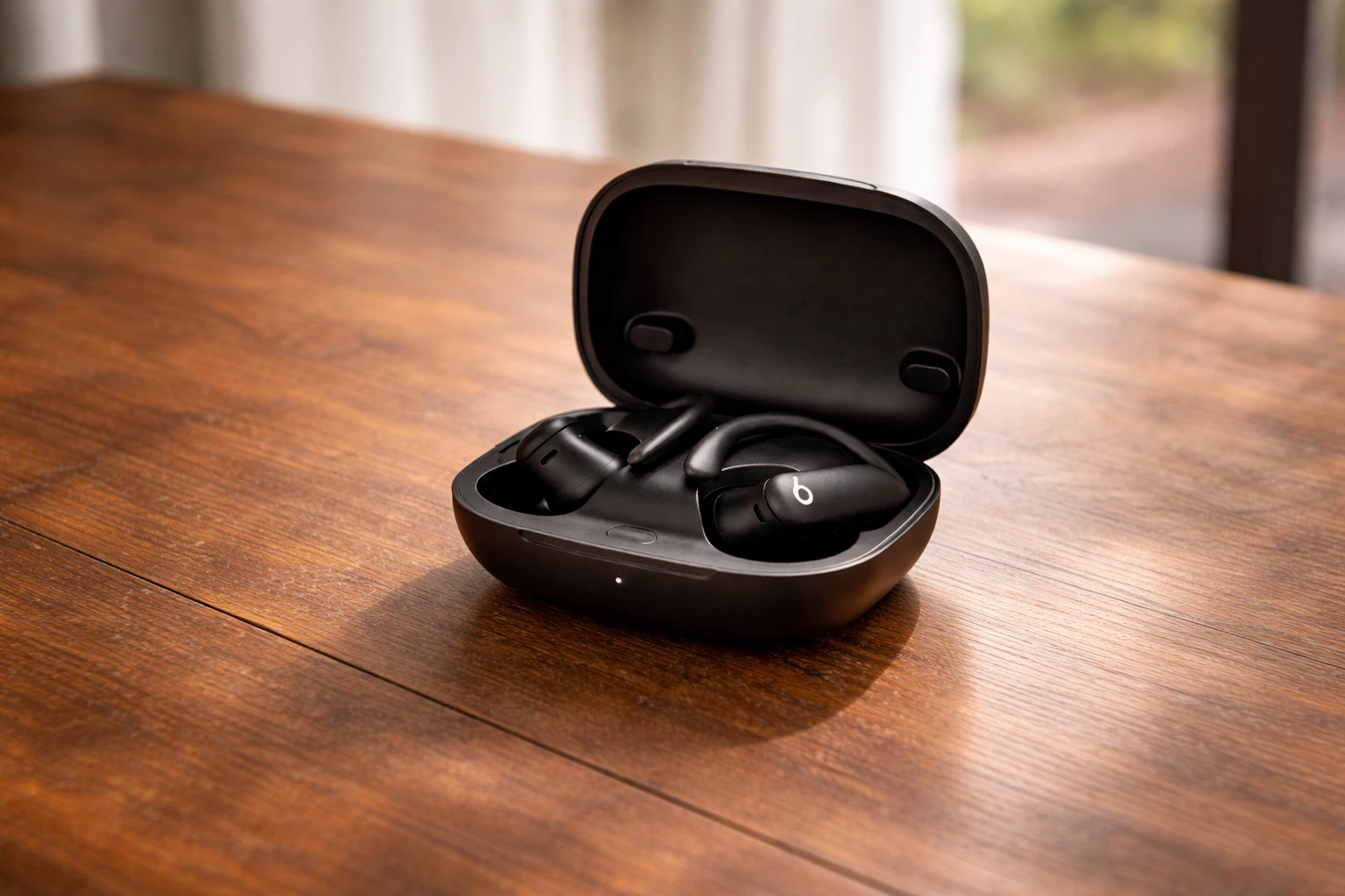 Beats Powerbeats Pro 2 black wireless earbuds in open charging case on wooden table