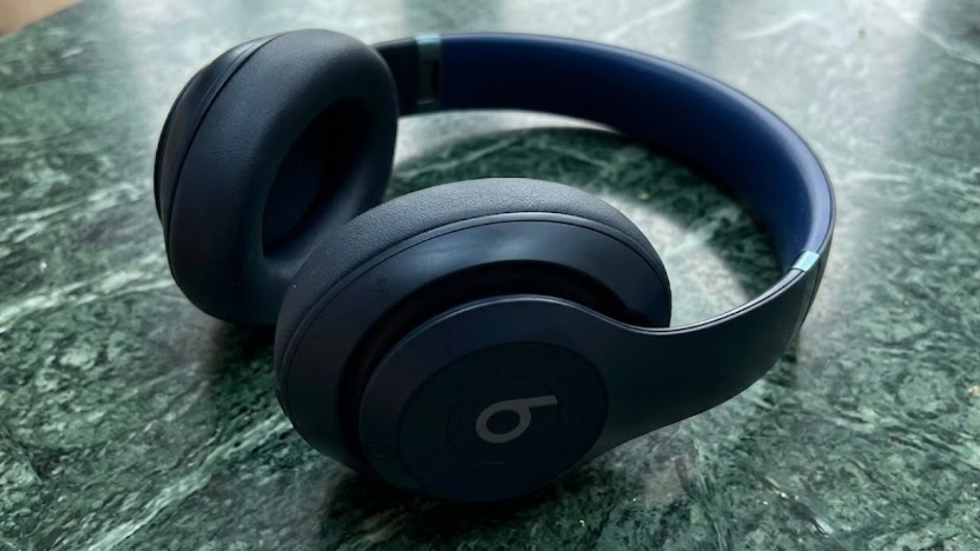 Beats studio pro over ear wireless headphones resting on green marble surface with soft ear cushions and adjustable headband design