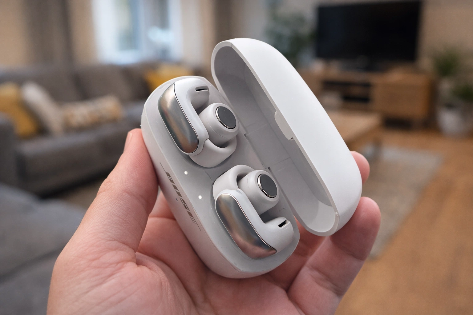 Bose Ultra Open Earbuds in white charging case held in hand indoors