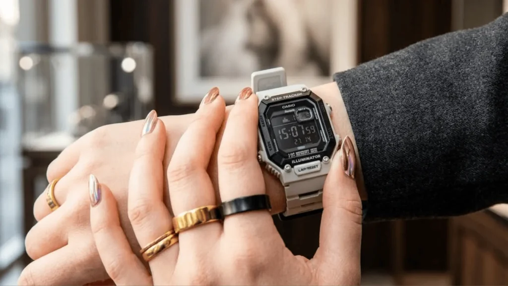 Casio digital watch worn on wrist with rings and manicured nails in an indoor lifestyle setting