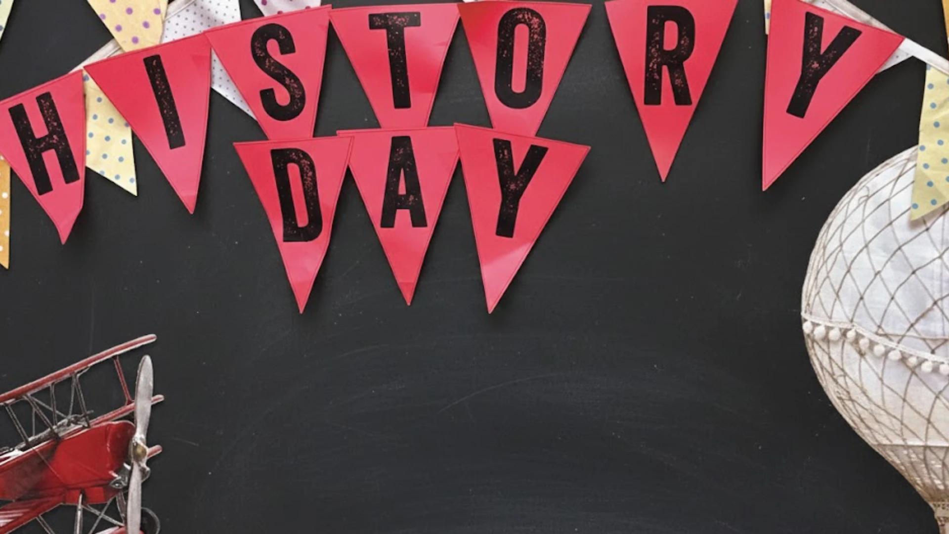 History Day banner with red pennants on chalkboard background featuring vintage airplane and hot air balloon decorations