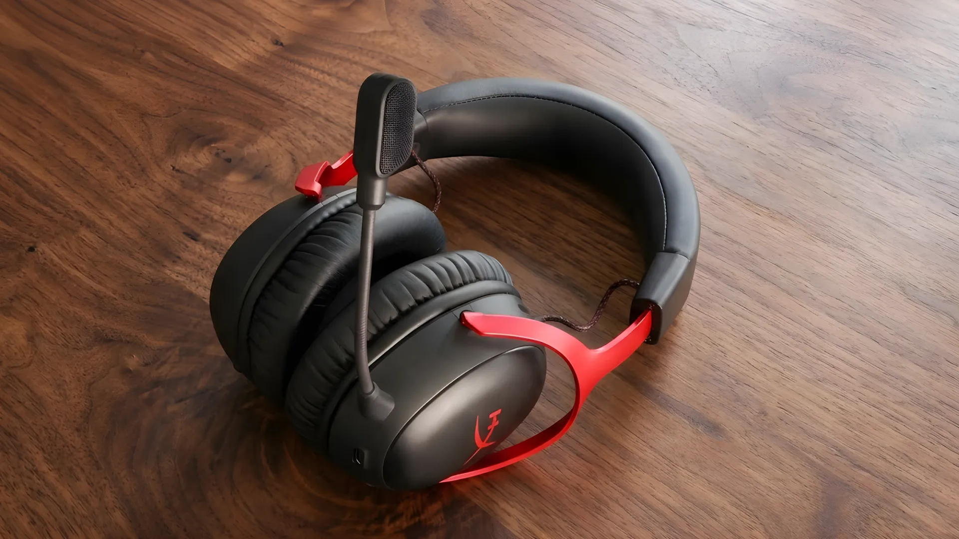 HyperX Cloud III gaming headset with boom mic on wooden desk, cushioned earcups and padded headband