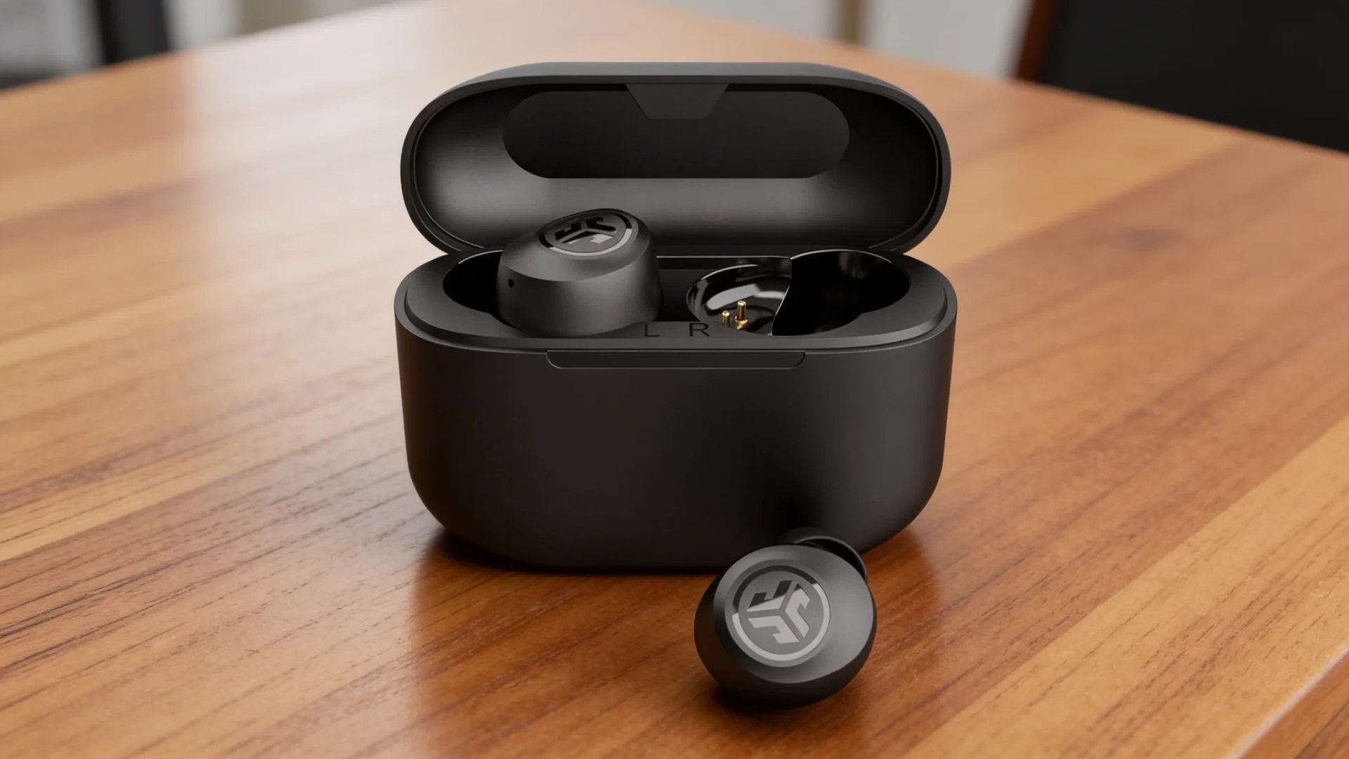 JLab Go Air Pop+ wireless earbuds in charging case placed on wooden table with one earbud outside the case