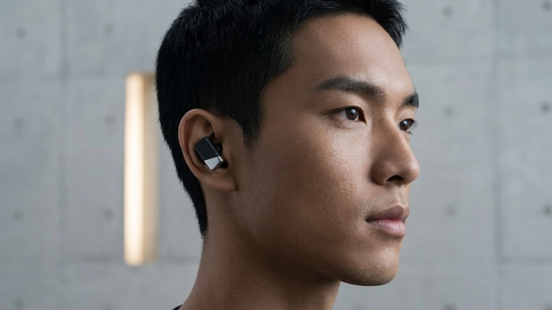 Man wearing Status Pro X wireless earbuds showing in ear fit and compact stem design during daily use