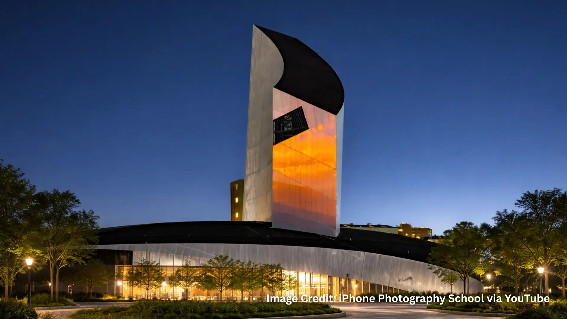 Modern tower above circular building at night captured with Night Mode on iPhone 16 Pro Max Camera showing clear sky