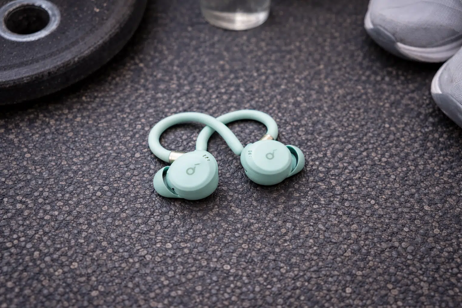 Soundcore Sport X20 wireless workout earbuds on gym floor near weights and shoes