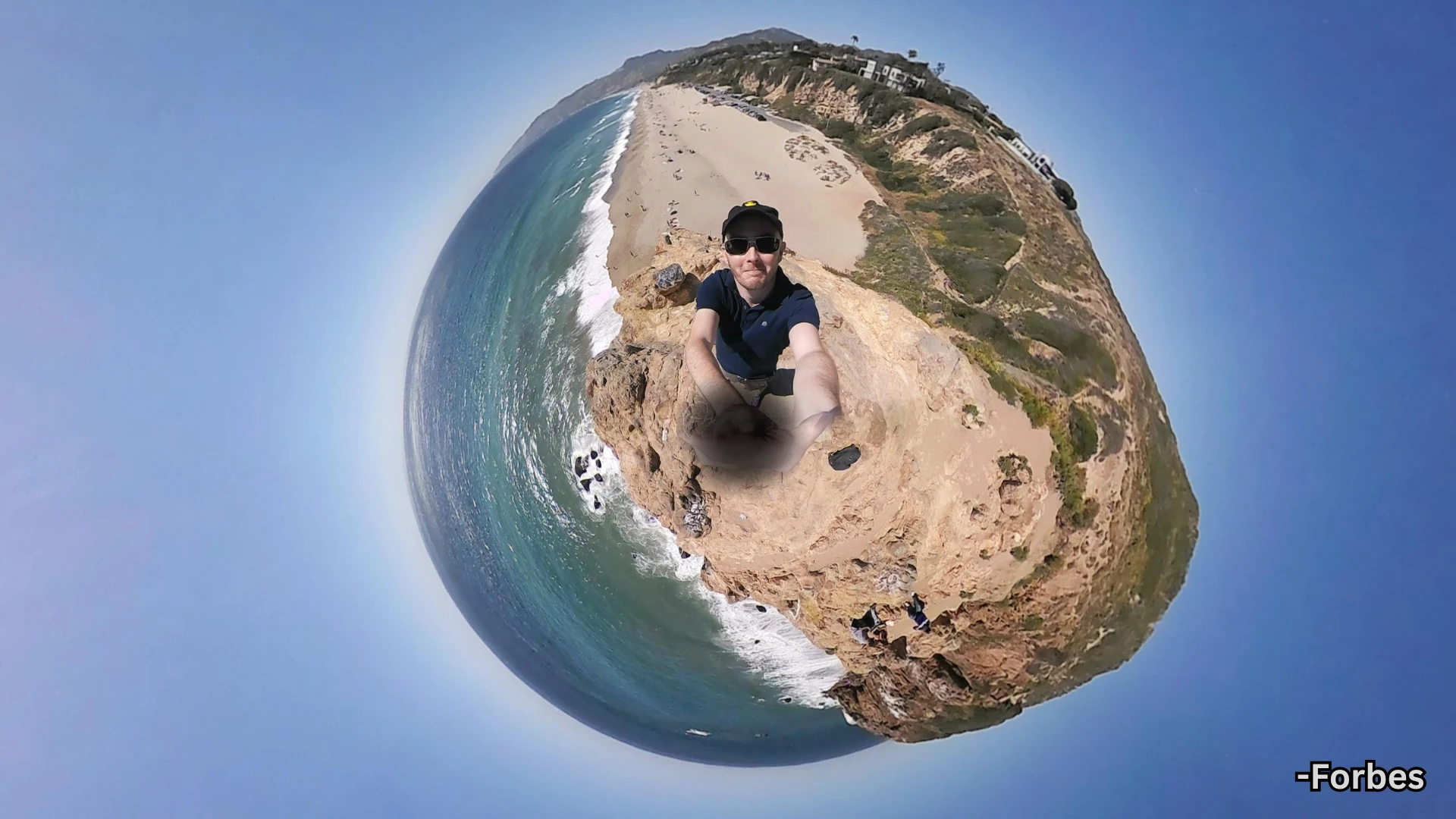 360 degree tiny planet shot from Insta360 showing person on cliff with beach, ocean, and coastline
