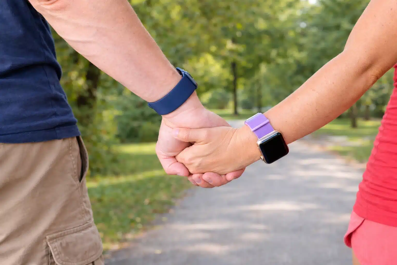 Couple holding hands outdoors wearing Apple Watches with different bands