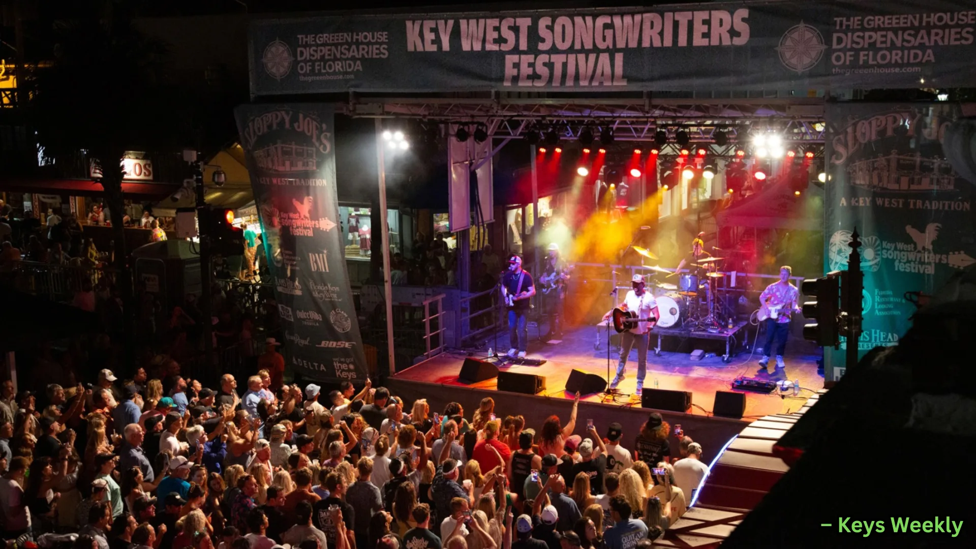 Crowd enjoying live music at Key West Songwriters Festival, band performing on lit stage at night