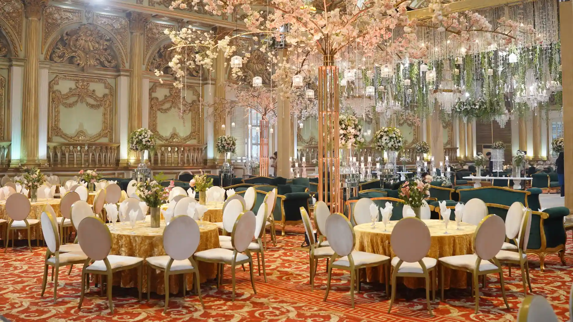 Elegant industrial event space with round banquet tables, white floral centerpieces, and a stage