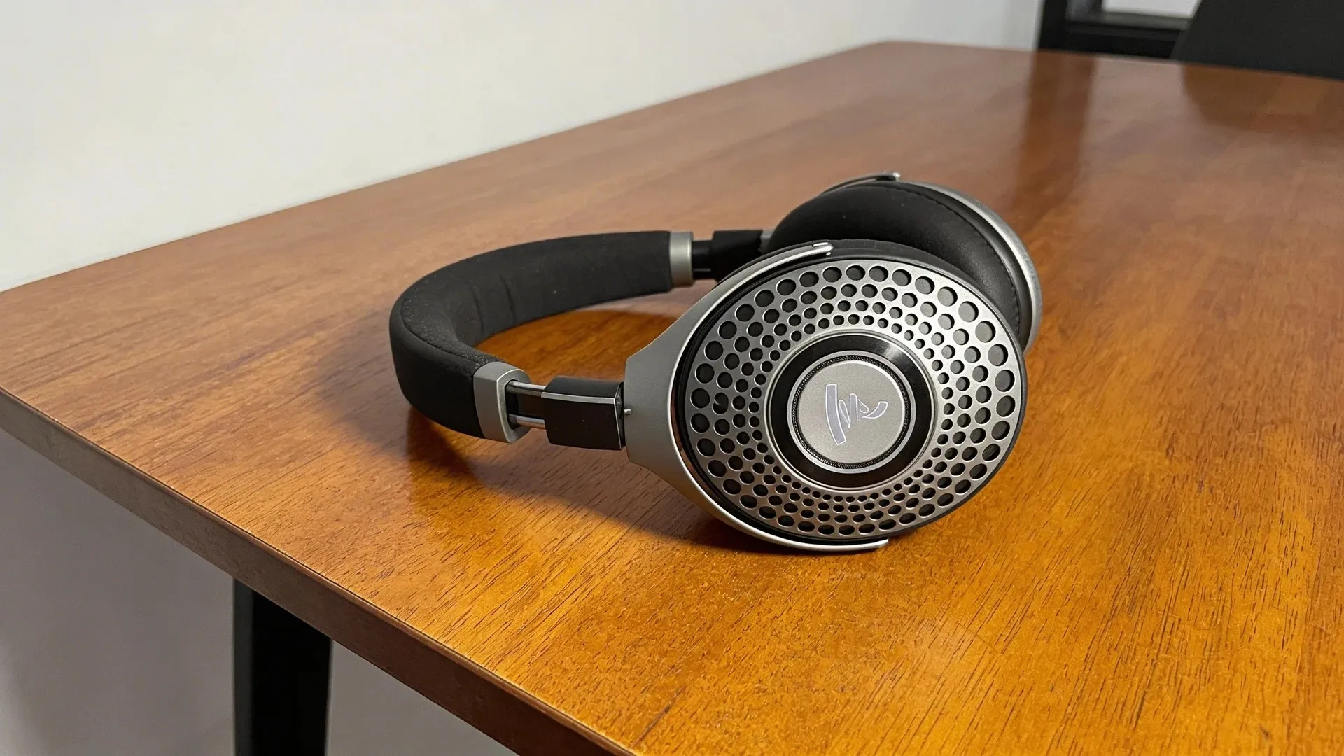 Focal Bathys headphones placed on wooden table showing premium build, metal grille design, and cushioned headband