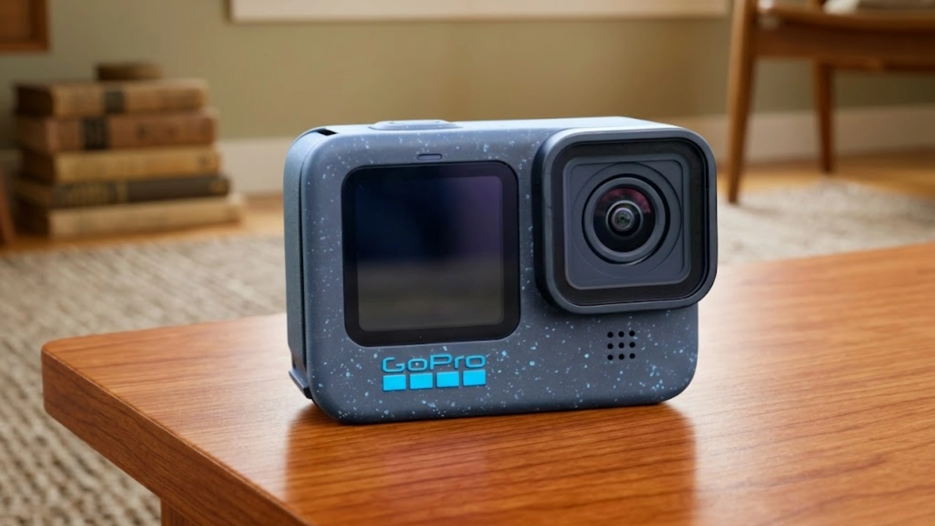 GoPro action camera placed on a wooden table indoors showing lens, front screen, and compact design in a home setting