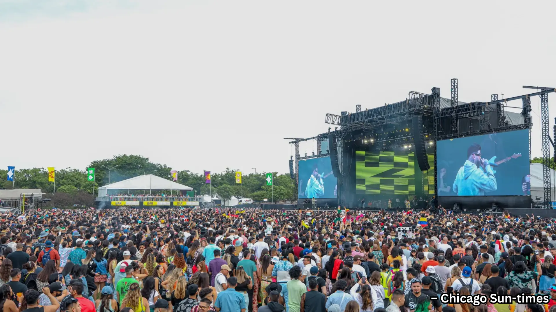 Huge crowd at outdoor music festival, main stage with large screens and live performance in open field