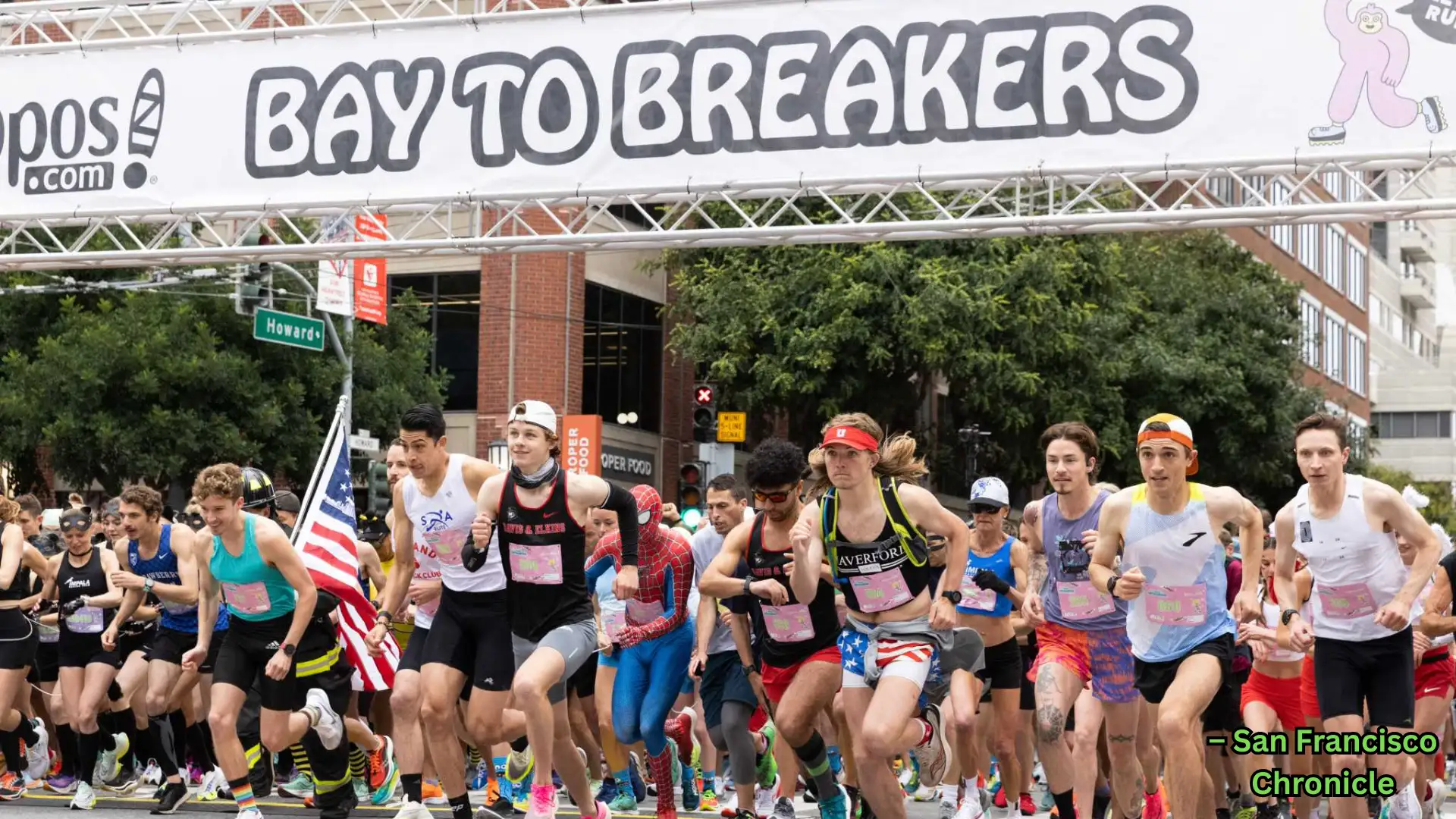 Runners start Bay to Breakers race in city street, crowd in costumes and athletic wear under banner
