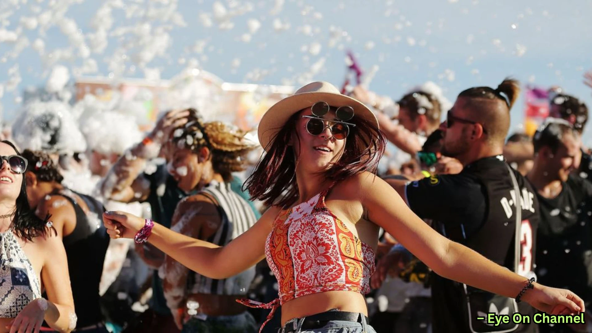 Young people dancing at outdoor foam party, smiling and enjoying music under bright daylight atmosphere