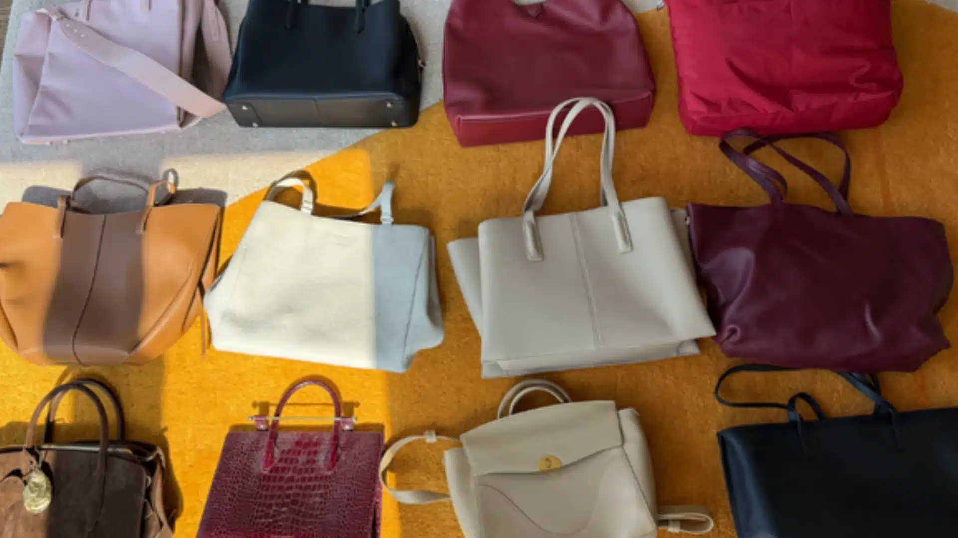 Assorted leather handbags in various colors and styles neatly arranged on floor in organized display