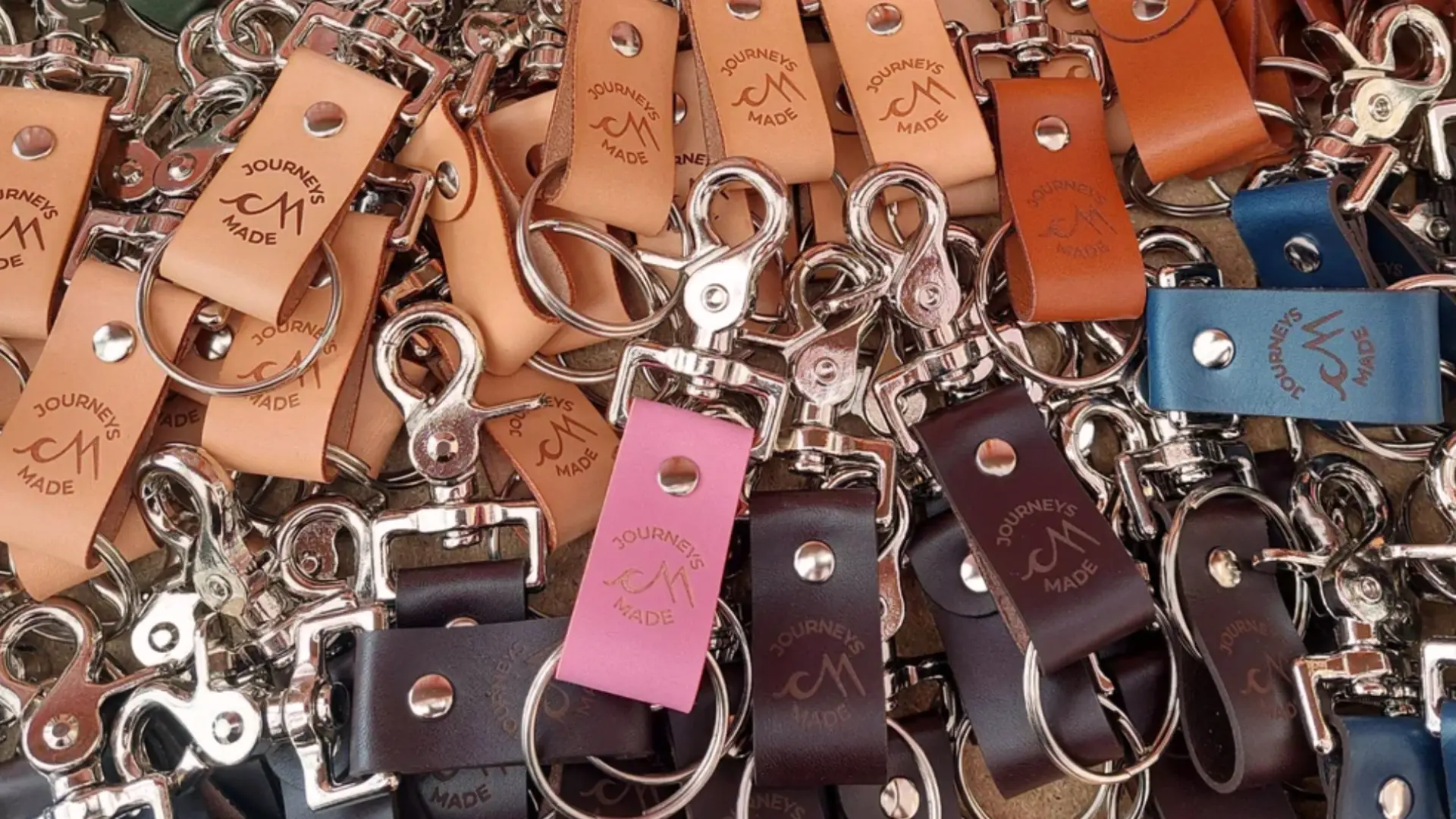 Assorted leather keychains with metal clips and engraved logos scattered in a detailed close up view