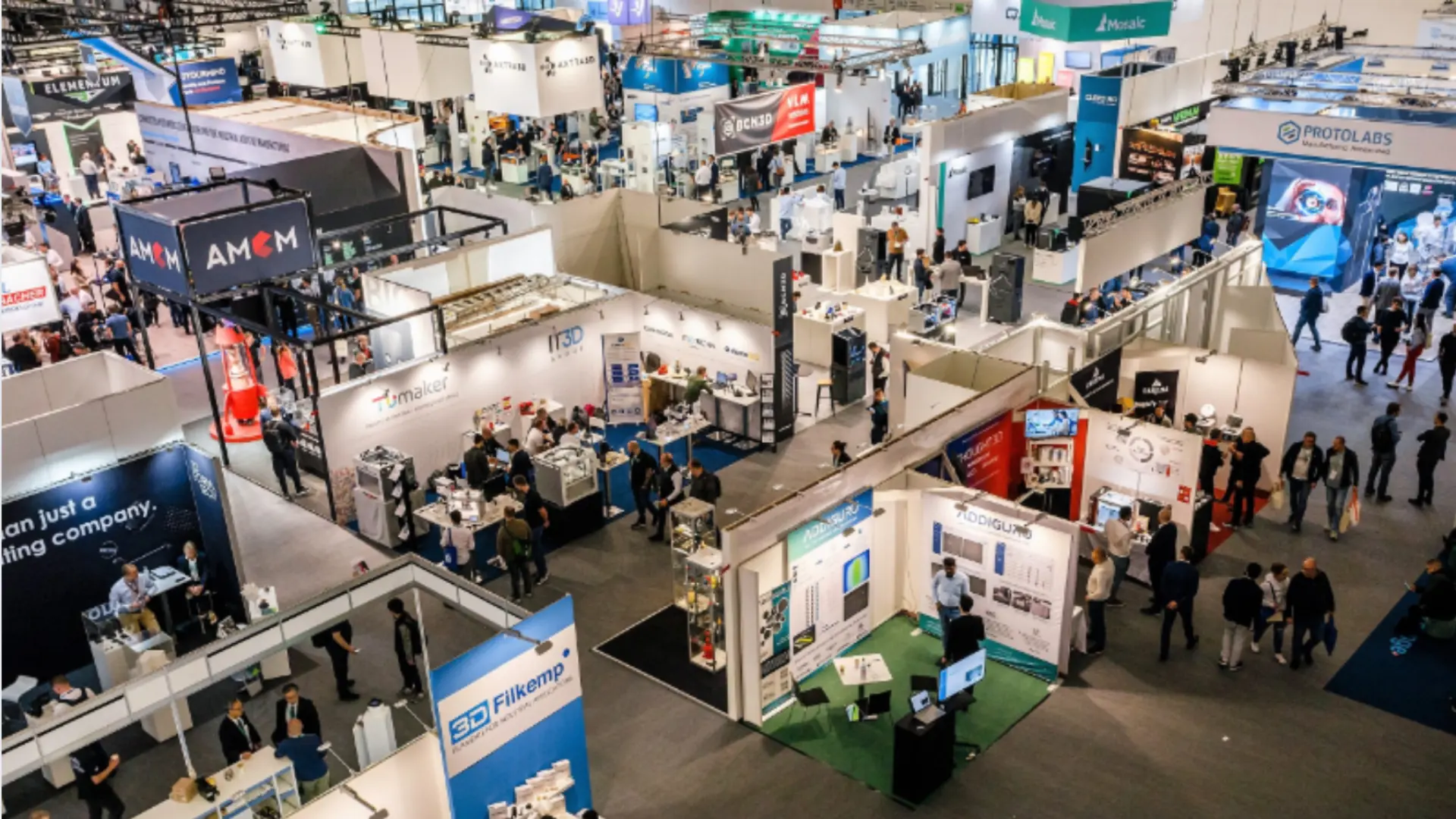 Busy trade show floor with multiple booths, exhibitors, and attendees exploring products and services