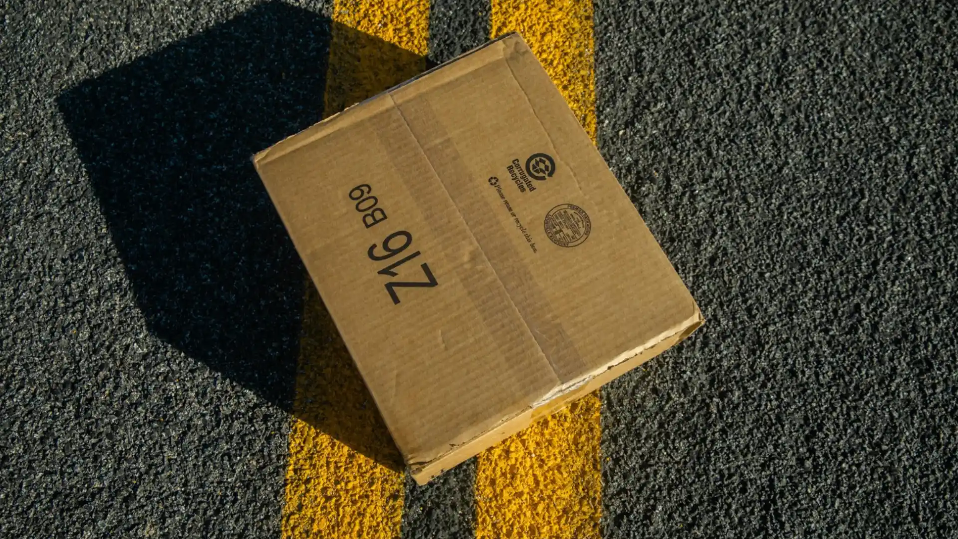 Cardboard mystery box placed on road with yellow lines, creating a suspenseful challenge setup
