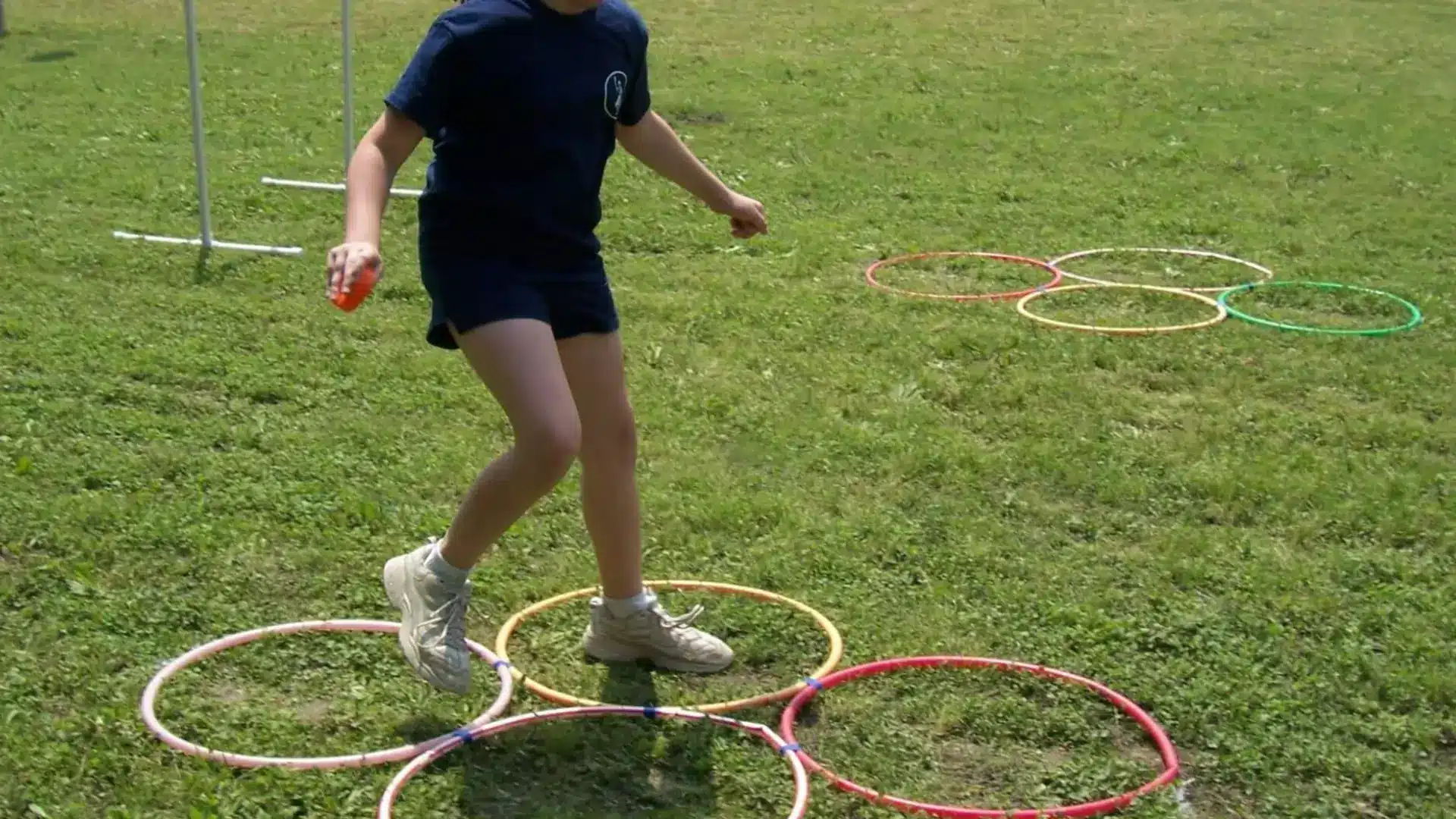 Child stepping through hula hoops during outdoor relay race, participating in a fun and active school field event