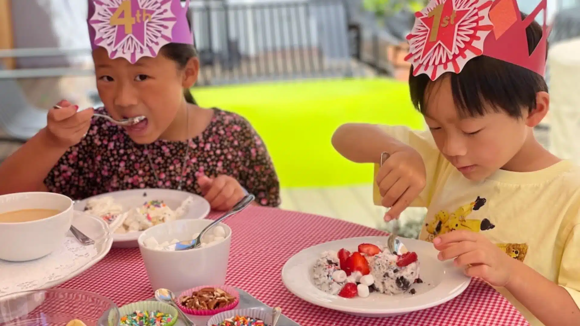 Children wearing party crowns enjoying ice cream with toppings at a bright and fun school celebration