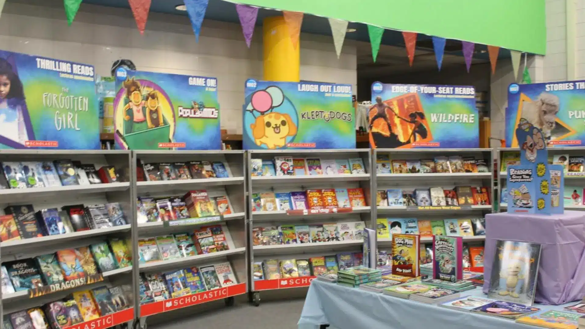 Colorful school book fair display with shelves of books, banners, and tables filled with popular children’s titles