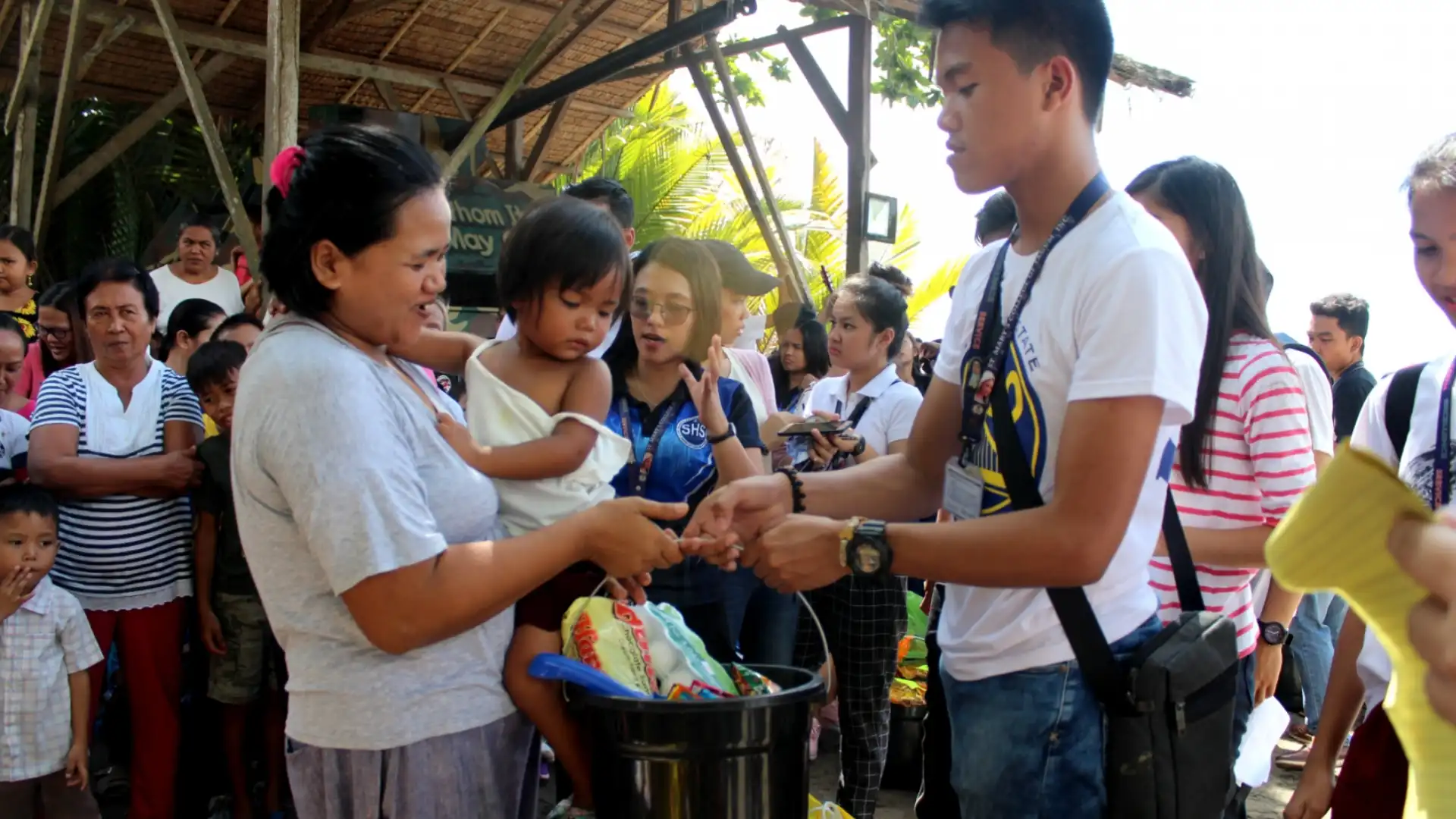 Community outreach volunteers distributing supplies to families, engaging with locals in outdoor setting