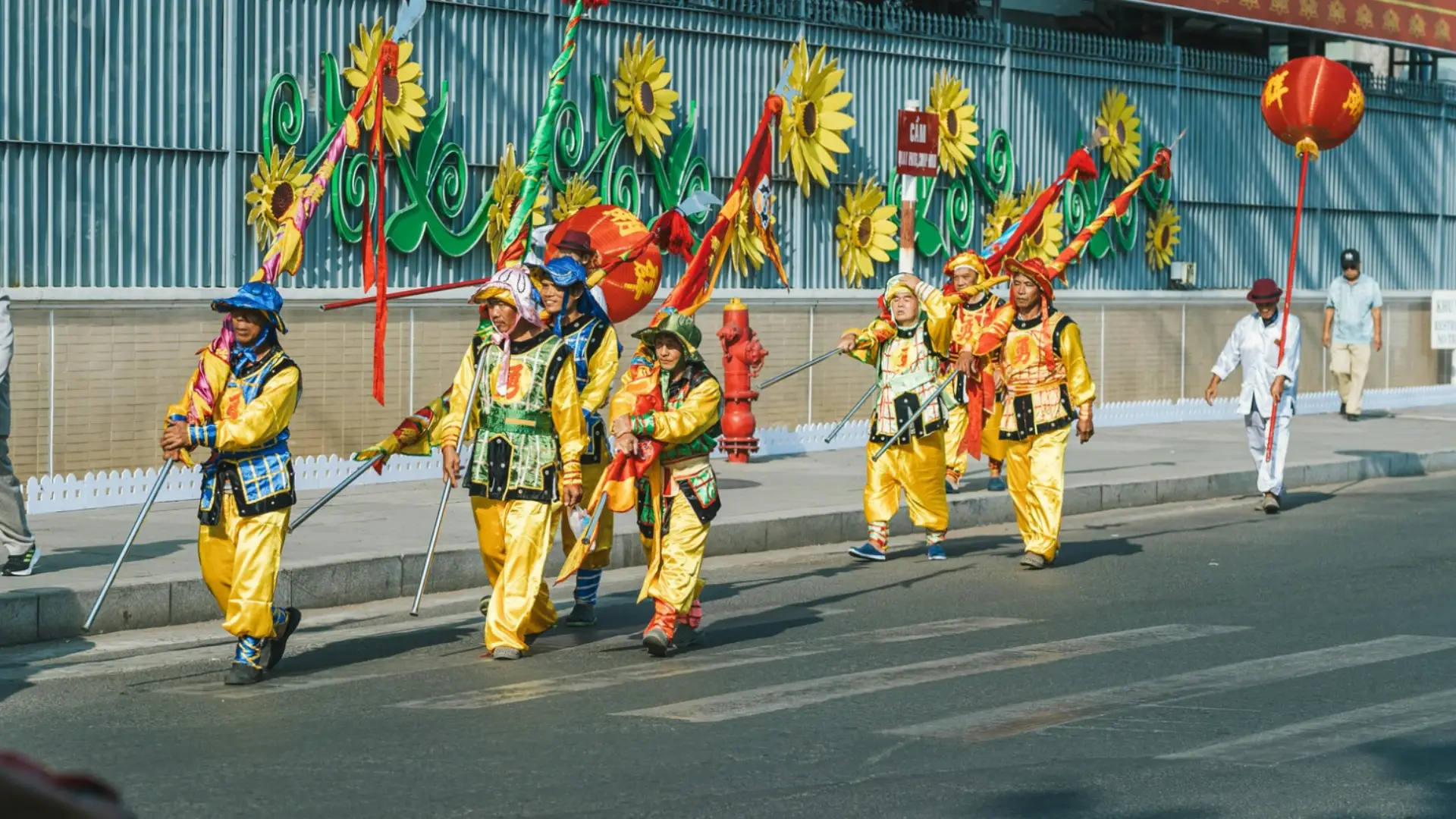 Cultural parade with performers in bright costumes carrying banners during a lively street celebration
