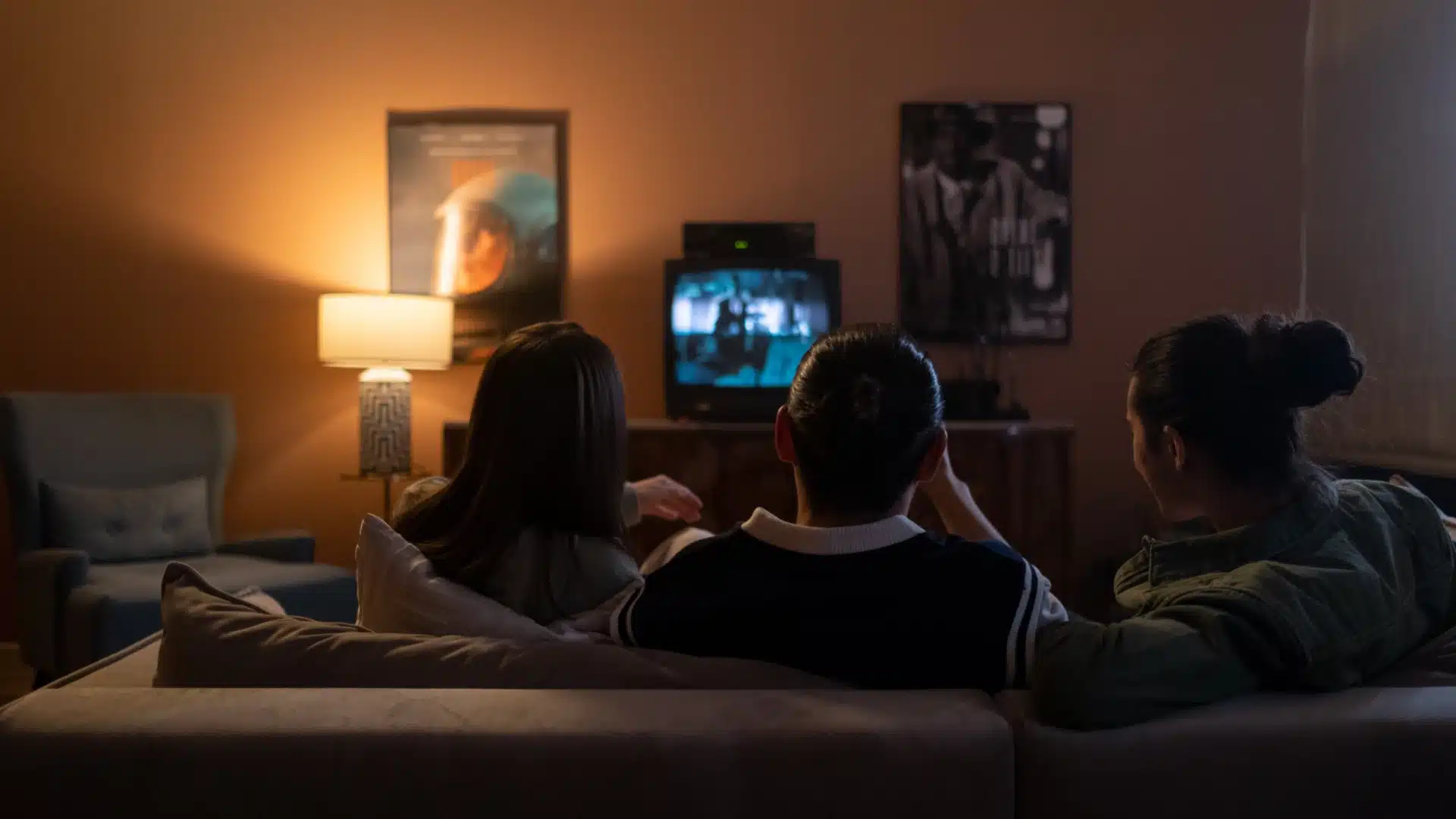 Families sitting together on a couch watching a movie at night, creating a cozy and relaxed school event atmosphere
