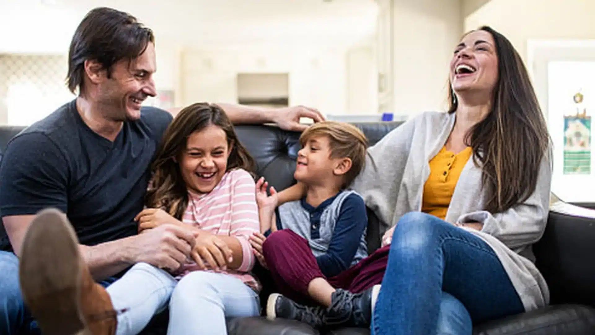 Family laughing together on couch during fun trivia night, enjoying games and bonding at home