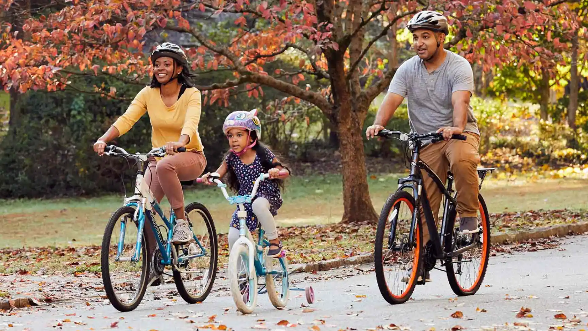 Family riding bicycles together in park during autumn, enjoying outdoor activity with colorful fall trees