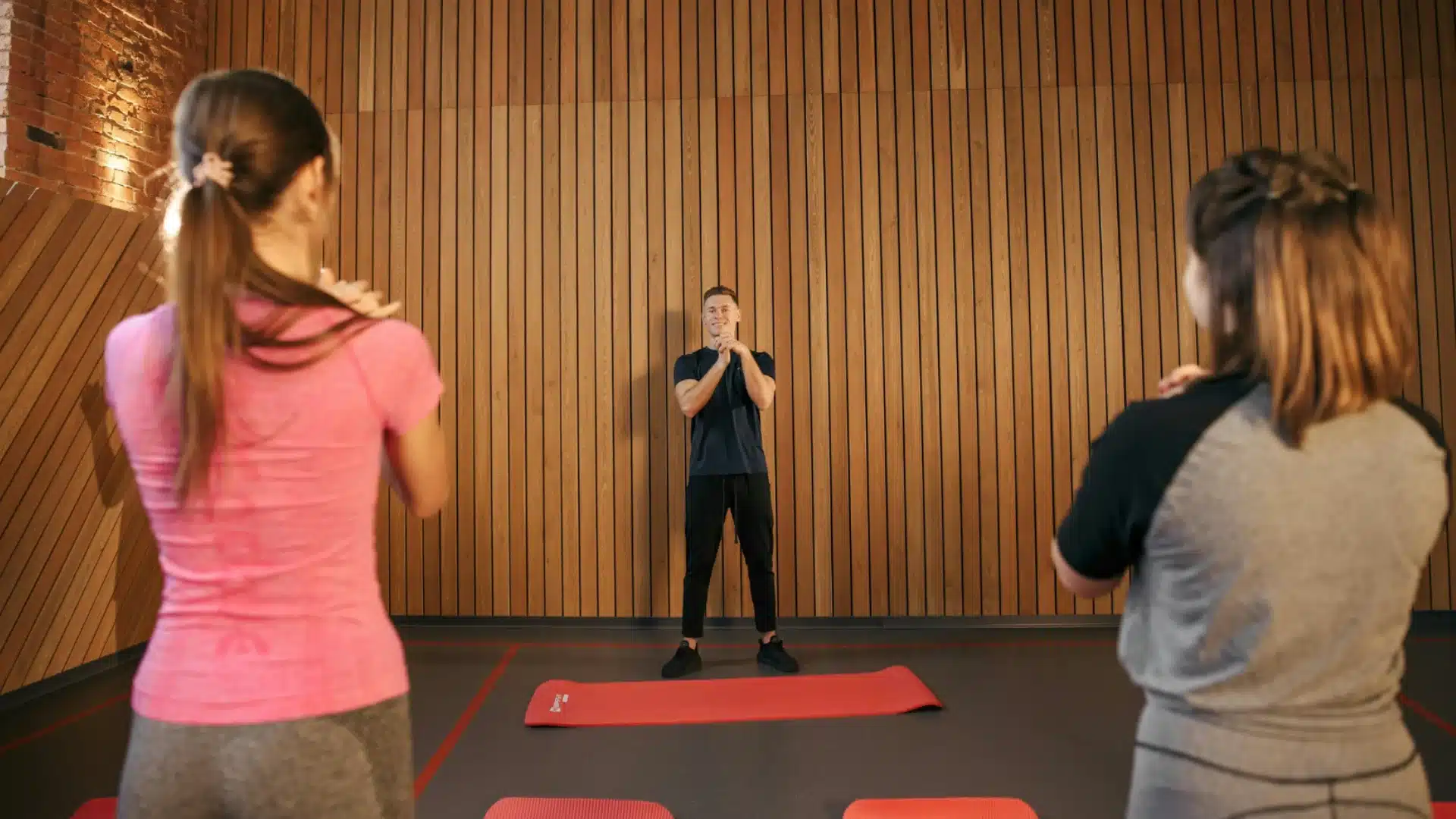Fitness instructor leading group workout session with participants on mats in indoor studio setting