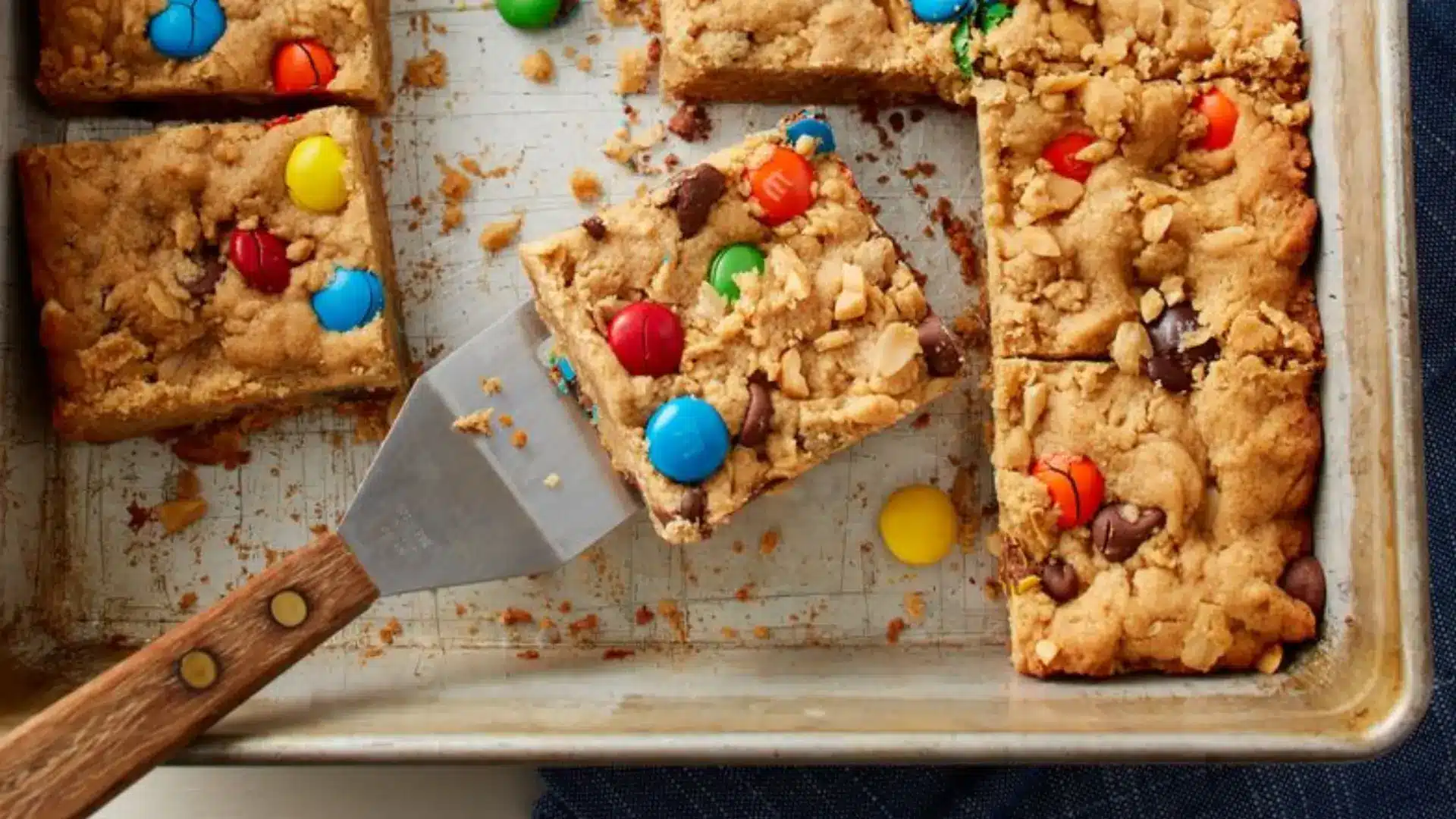 Freshly baked cookie bars with chocolate and candy toppings on tray, ready for school bake sale or bake-off