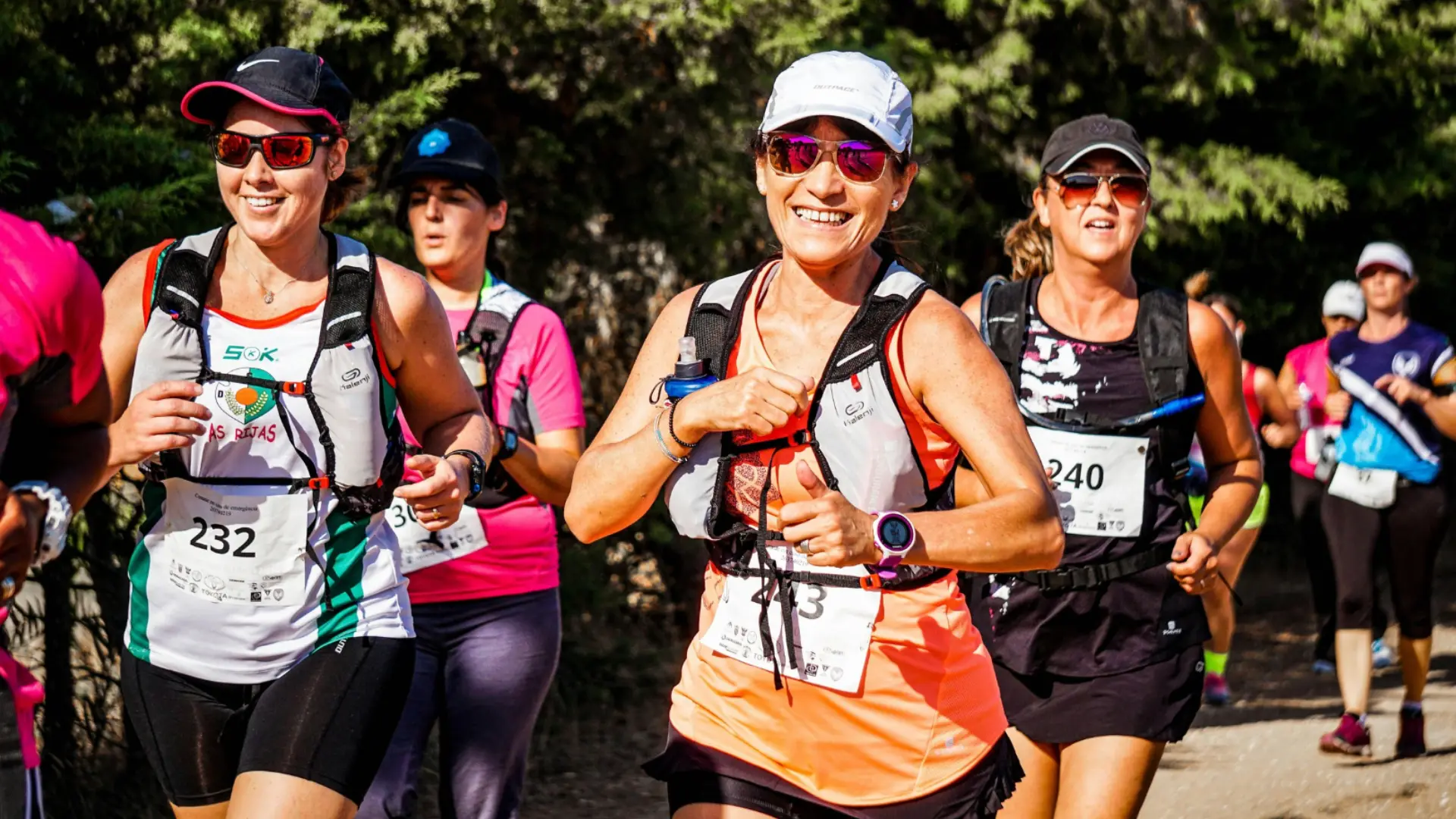 Group of runners wearing race bibs jogging outdoors during organized marathon or charity run event