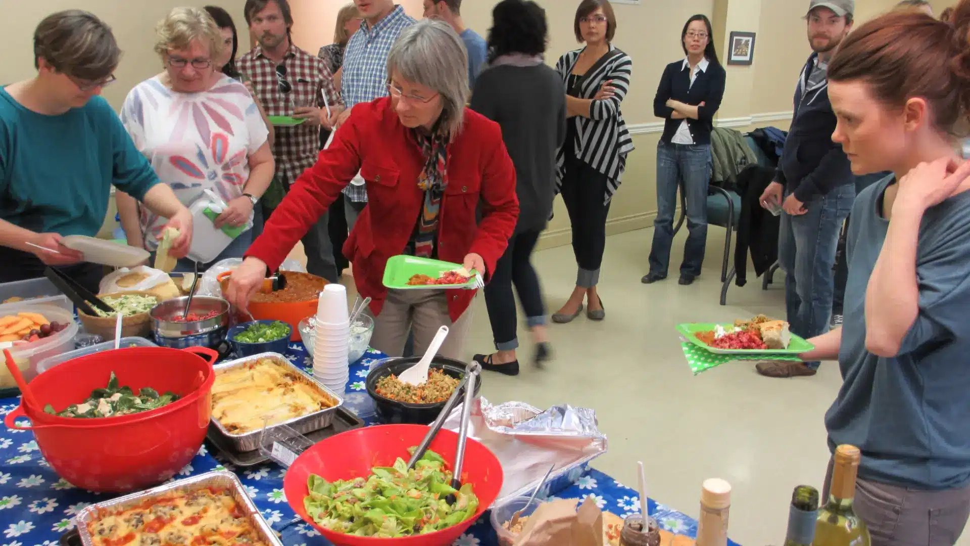 Group sharing diverse homemade dishes at potluck, celebrating culture and community connection indoors