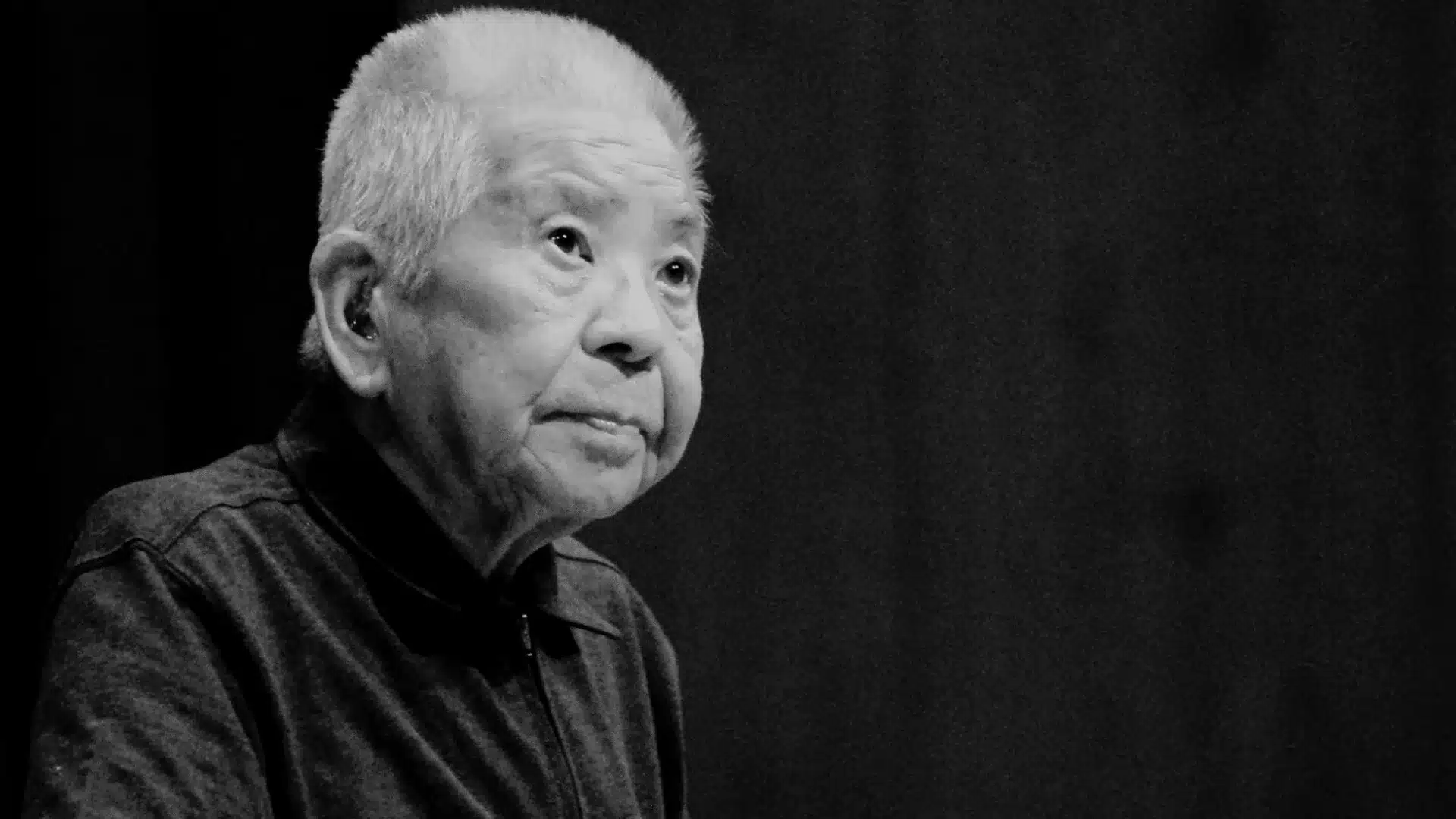 Black and white portrait of elderly man who survived two atomic bomb attack with short hair looking upward