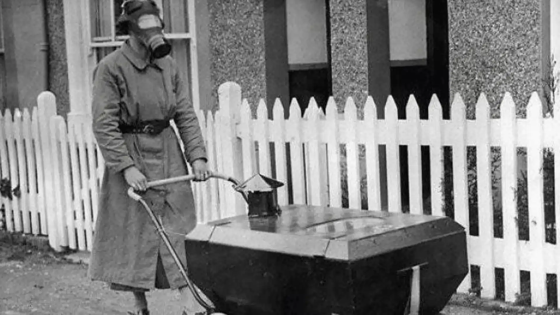 Old photo of person wearing gas mask pushing sealed baby carriage designed for protection from toxic air