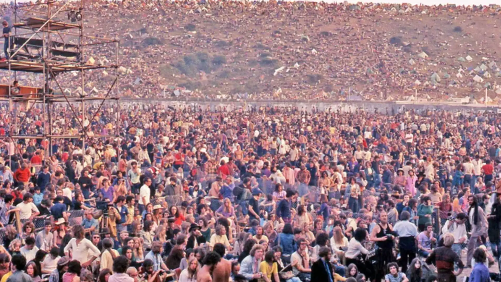 Massive crowd at Isle of Wight Festival sitting and standing across open field during daytime concert