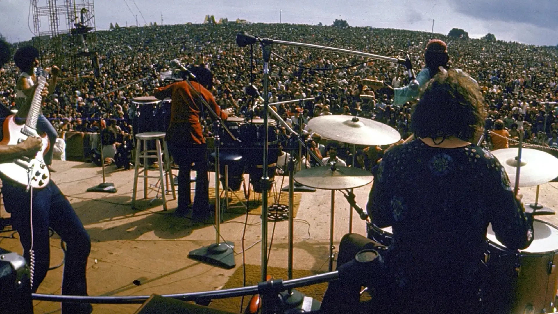 The Who performing live on stage with drummer and band facing massive outdoor festival crowd
