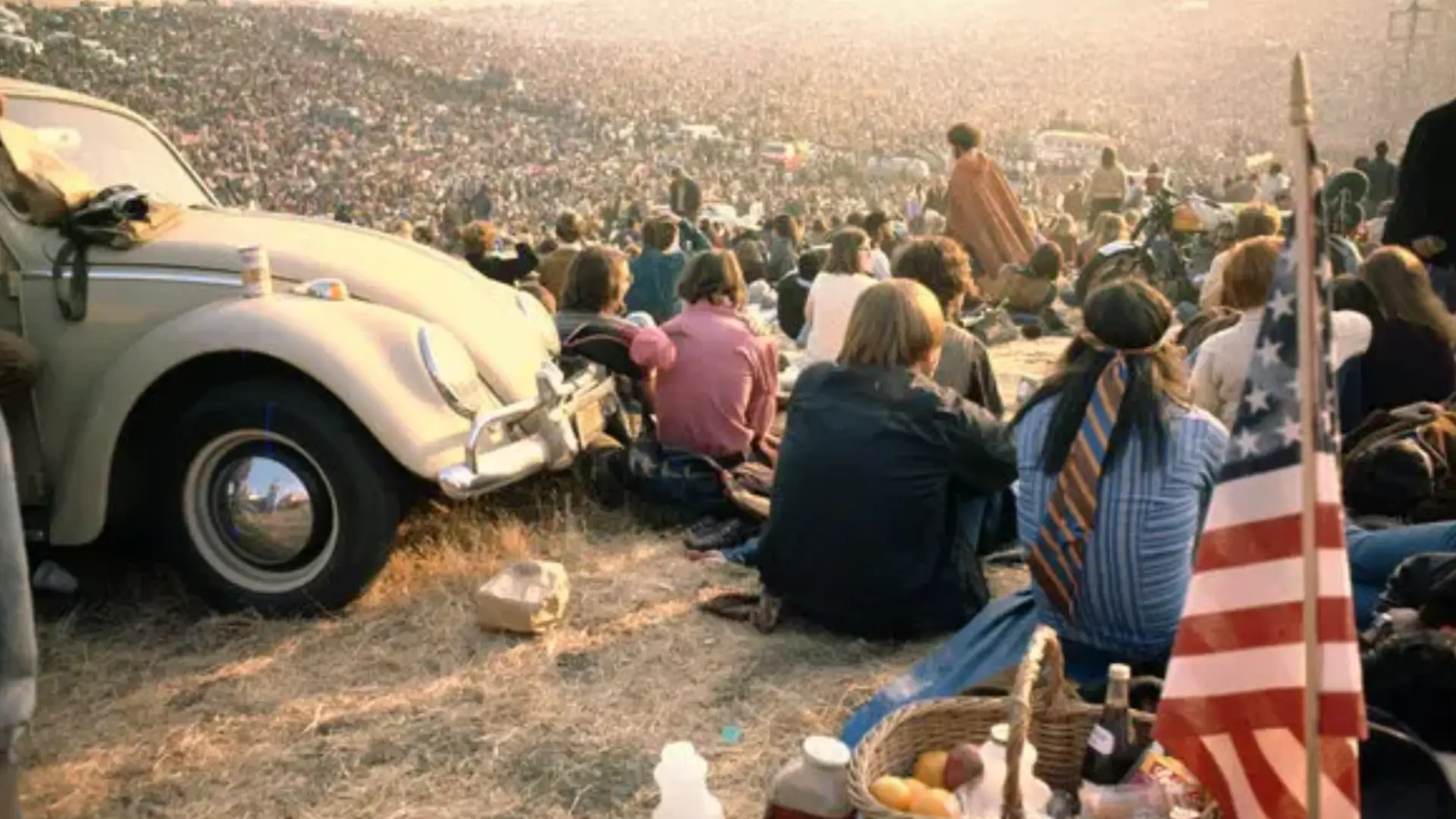 Huge crowd gathered at Altamont Speedway festival with people sitting on ground and watching stage