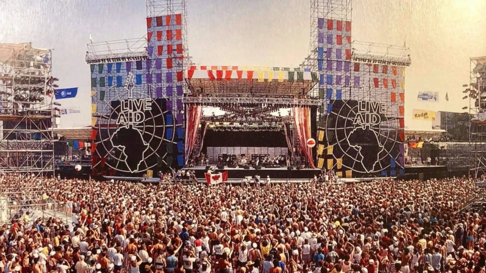 Wide view of Live Aid concert stage with massive audience and iconic setup filled with cheering fans