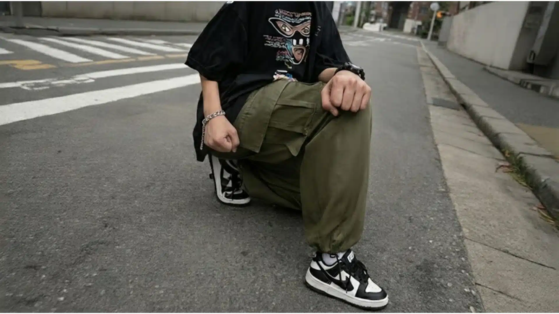 Person wearing oversized tee with baggy cargo pants and sneakers on city street
