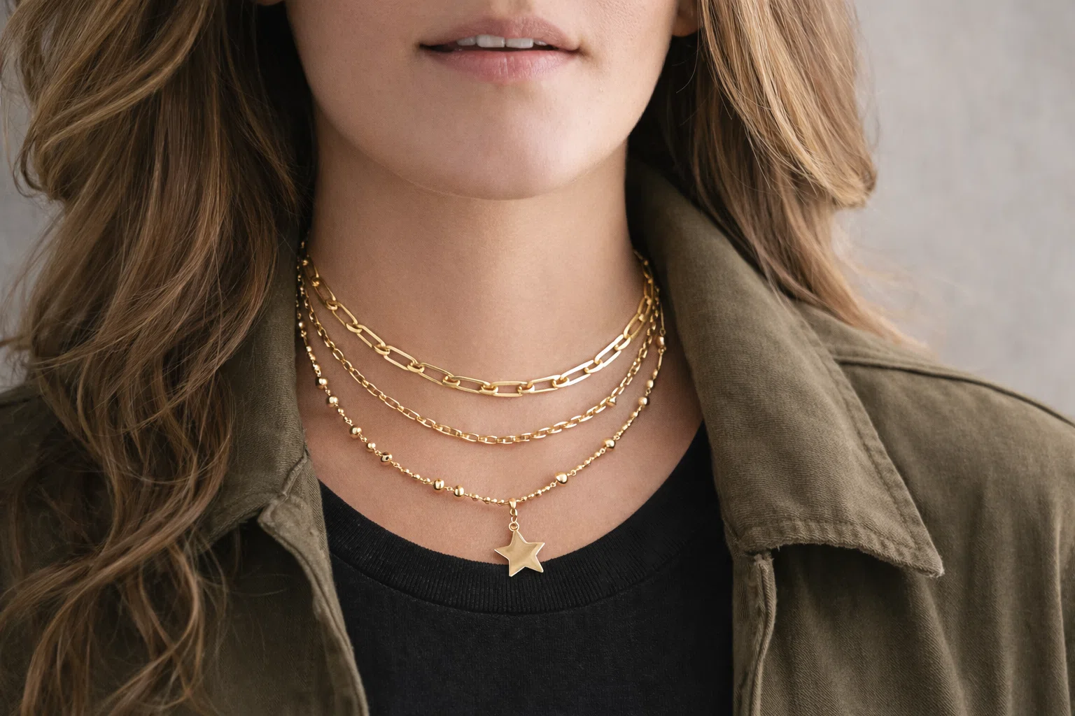 Close up of layered gold chain necklaces with star pendant worn by a lady