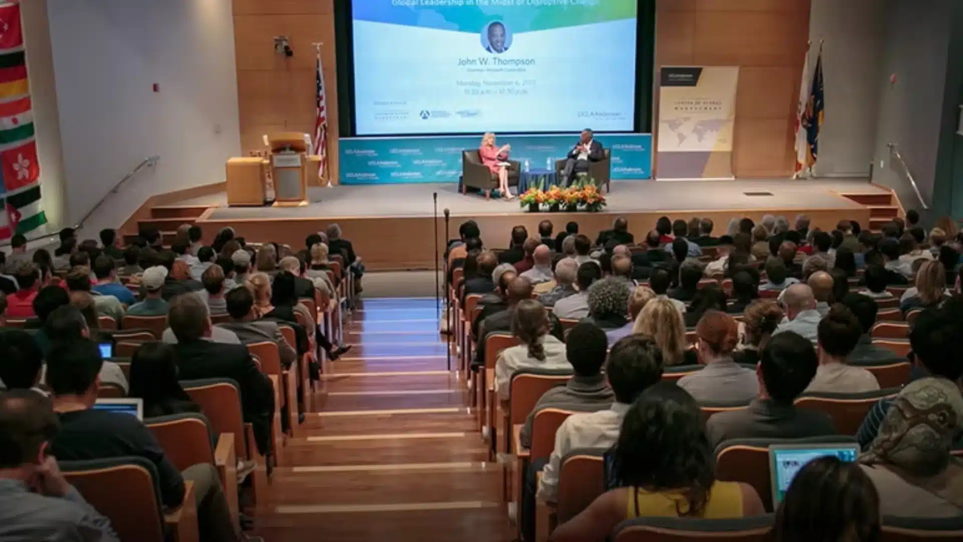 Large conference audience listening to speakers on stage during formal business or leadership event